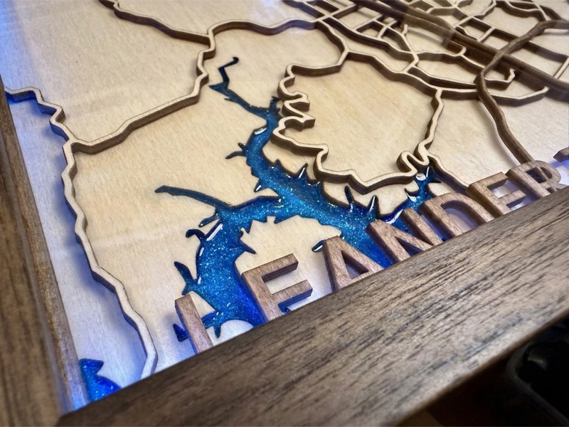 Close-up of layered map artwork with glossy resin-filled blue lake detail.